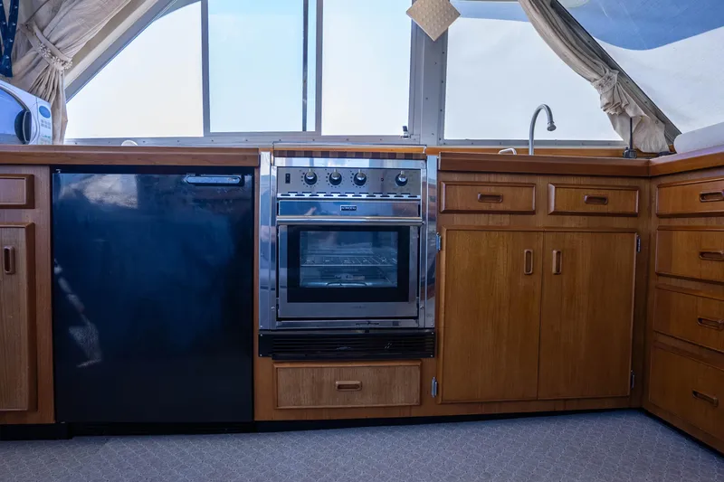 Barefoot Girl Yacht Photos Pics 1984 Bertram 35 Convertible yacht kitchen with wood cabinets and modern appliances.