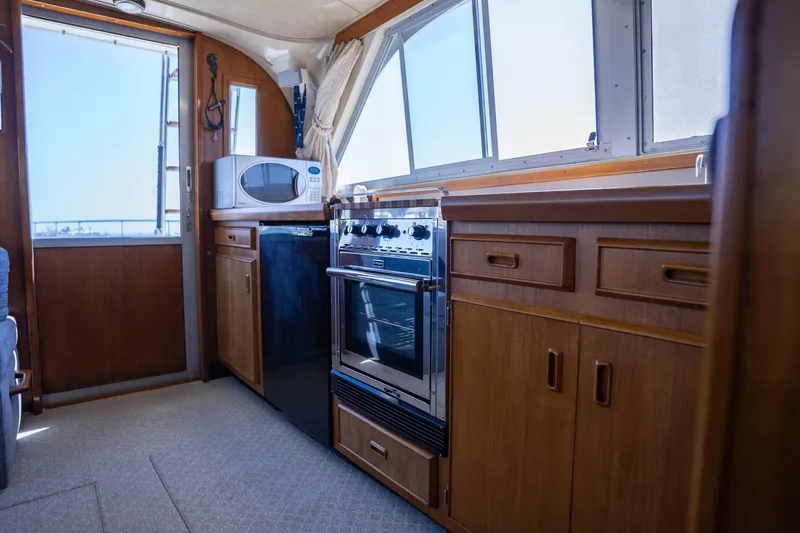 Barefoot Girl Yacht Photos Pics Interior of 1984 Bertram 35 Convertible yacht kitchen with stove, microwave, and wooden cabinets.
