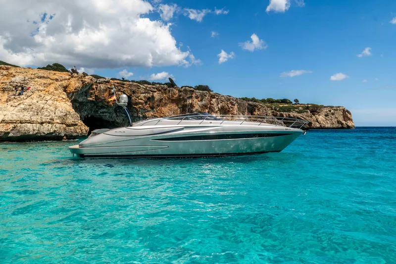 Vimojal II Yacht Photos Pics 2009 Riva 52' le yacht in turquoise waters near rocky cliffs under a blue sky.