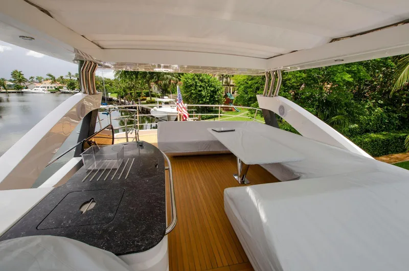  Yacht Photos Pics Sunseeker 75 Yacht 2018, spacious upper deck with seating and dining area, docked by lush greenery.