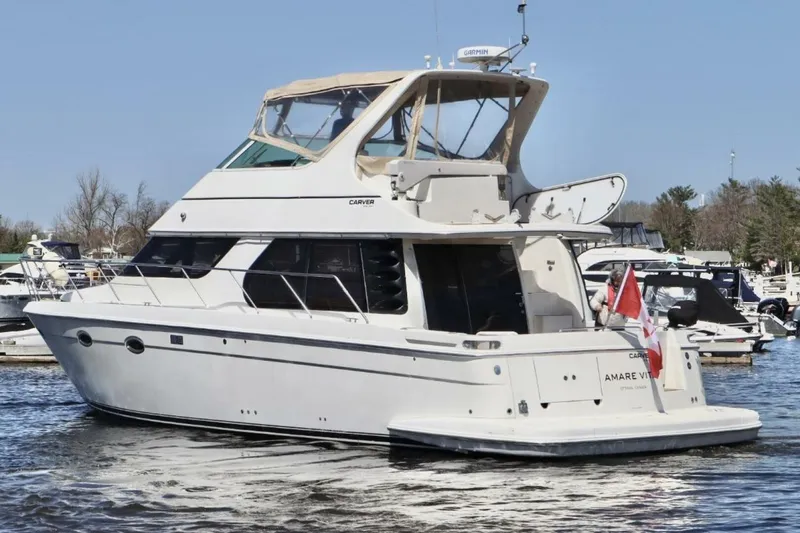  Yacht Photos Pics 2004 Carver 460 Voyager yacht docked in a marina, featuring a sleek white design.
