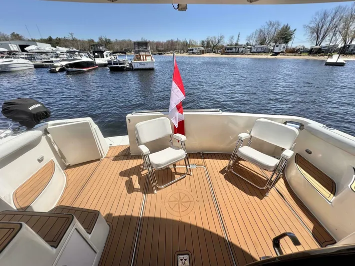  Yacht Photos Pics 2004 Carver 460 Voyager yacht deck with chairs and a flag, overlooking a marina.