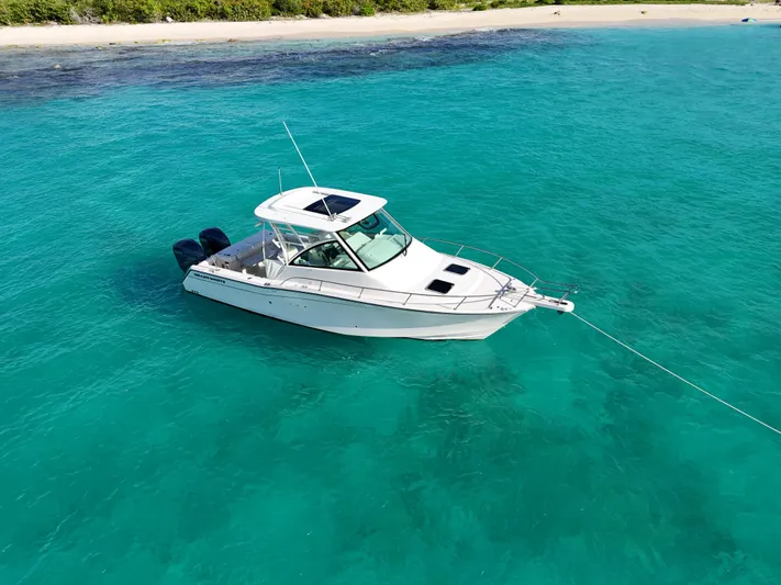  Yacht Photos Pics 2021 Grady-White Express 330 boat anchored in clear turquoise water near a sandy beach.