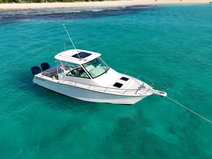  Yacht Photos Pics 2021 Grady-White Express 330 boat anchored in clear turquoise water near a sandy beach.