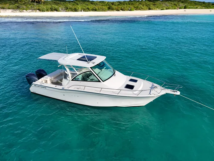  Yacht Photos Pics 2021 Grady-White Express 330 boat anchored in clear turquoise water near a sandy beach.