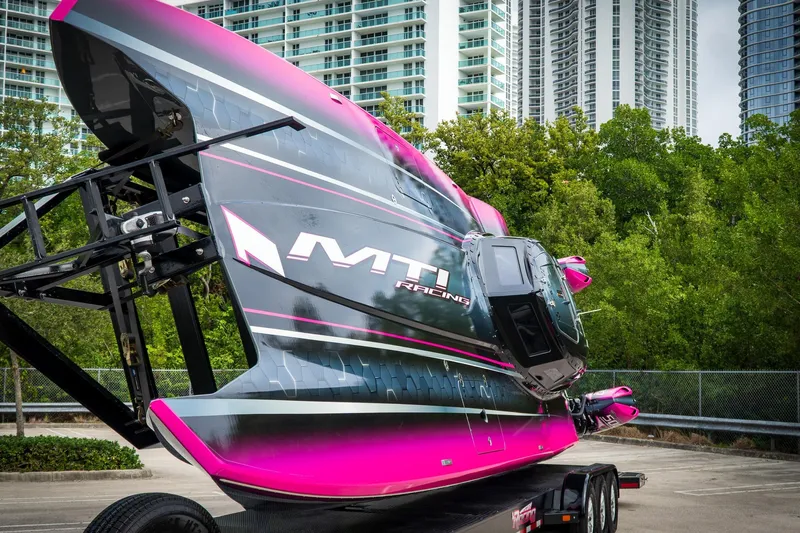  Yacht Photos Pics 2023 MTI 390XR racing boat on trailer, vibrant pink and black design, urban background.