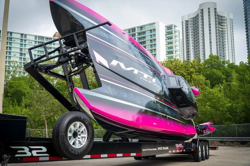  Yacht Photos Pics 2023 MTI 390XR powerboat on trailer, vibrant pink and black design, urban backdrop.
