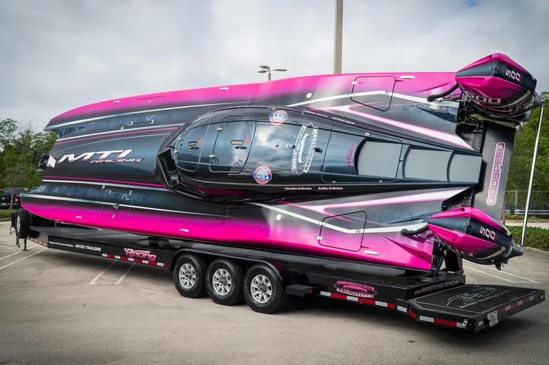  Yacht Photos Pics 2023 MTI 390XR powerboat on trailer, vibrant pink and black design, parked outdoors.