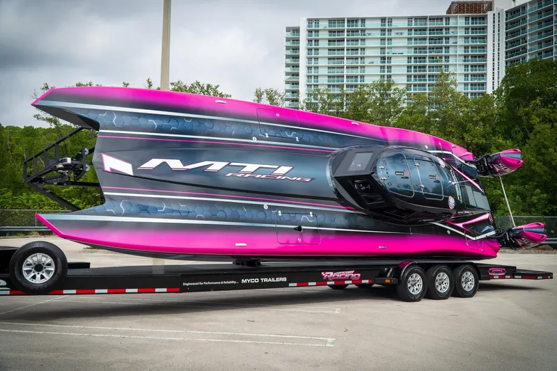  Yacht Photos Pics 2023 MTI 390XR powerboat on trailer, vibrant pink and black design, parked outdoors.