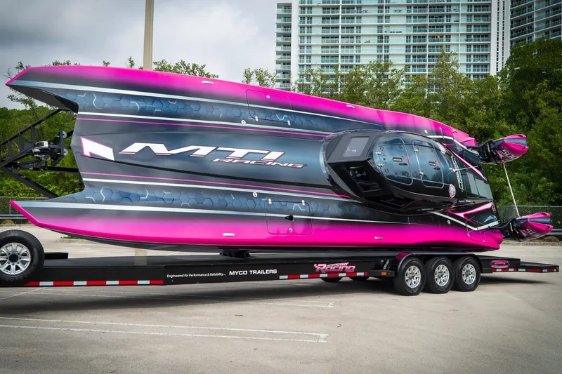 Yacht Photos Pics 2023 MTI 390XR powerboat on trailer, vibrant pink and black design, parked outdoors.
