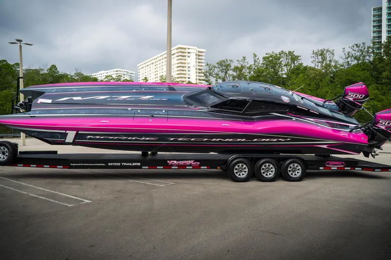  Yacht Photos Pics 2023 MTI 390XR powerboat with vibrant pink and black design on a trailer.