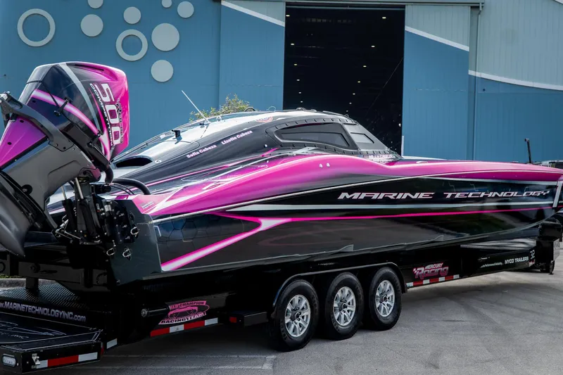  Yacht Photos Pics 2023 MTI 390XR powerboat with vibrant pink and black design, parked on a trailer.