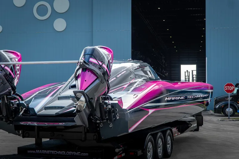  Yacht Photos Pics 2023 MTI 390XR powerboat with vibrant pink accents, parked outside a large blue building.