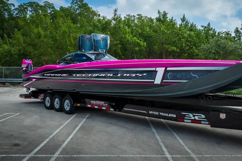  Yacht Photos Pics 2023 MTI 390XR powerboat on trailer, vibrant pink and black design, parked outdoors.