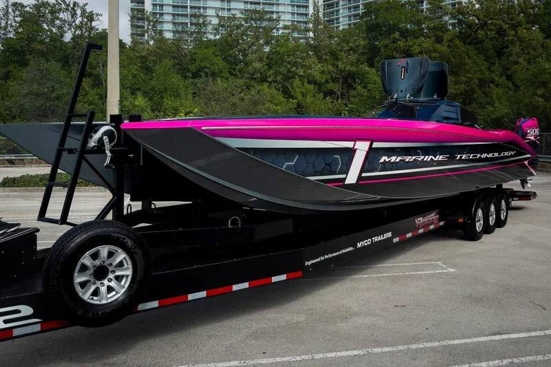  Yacht Photos Pics 2023 MTI 390XR powerboat on trailer, vibrant pink and black design, parked outdoors.