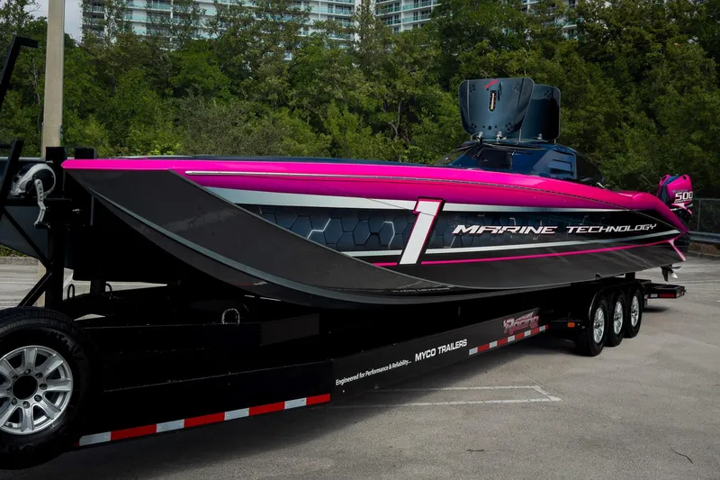  Yacht Photos Pics 2023 MTI 390XR powerboat on trailer, vibrant pink and black design, parked outdoors.