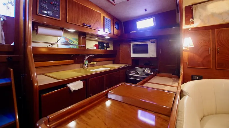 Forever Young Yacht Photos Pics Luxurious kitchen interior of 2000 Amel Super Maramu yacht with wooden cabinetry and modern amenities.