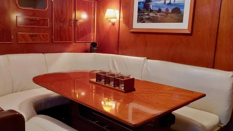 Forever Young Yacht Photos Pics Luxurious interior of 2000 Amel Super Maramu yacht with wooden table and white seating.