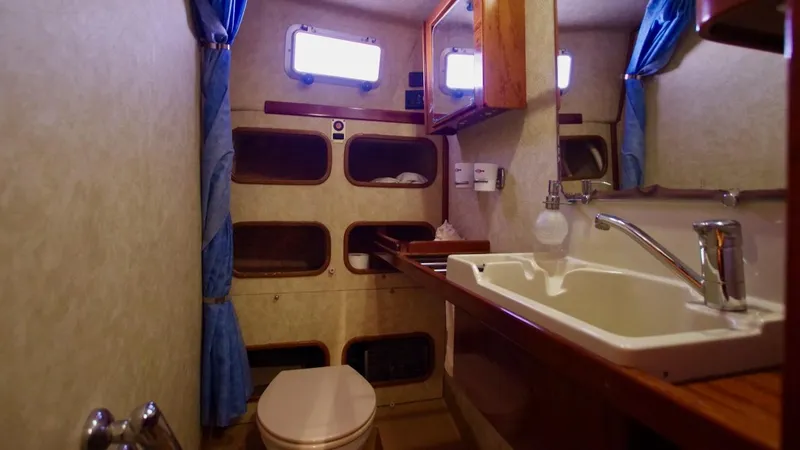 Forever Young Yacht Photos Pics Bathroom interior of 2000 Amel Super Maramu yacht with sink, toilet, and storage shelves.