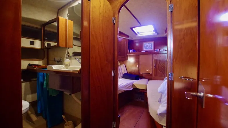 Forever Young Yacht Photos Pics Interior of 2000 Amel Super Maramu yacht, featuring cozy cabin and bathroom with wooden finishes.