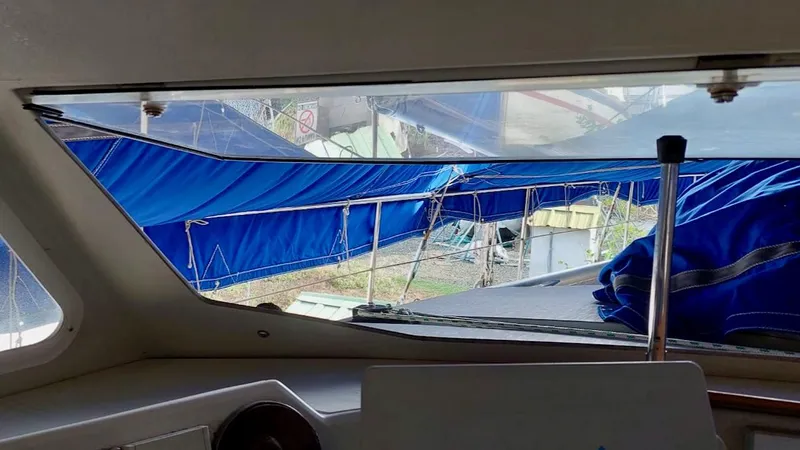 Forever Young Yacht Photos Pics Interior view from Amel Super Maramu 2000 yacht, showcasing blue tarpaulin and outdoor scenery.