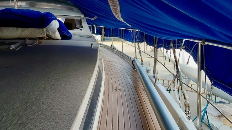 Forever Young Yacht Photos Pics Deck view of 2000 Amel Super Maramu sailboat with blue covers and wooden flooring.