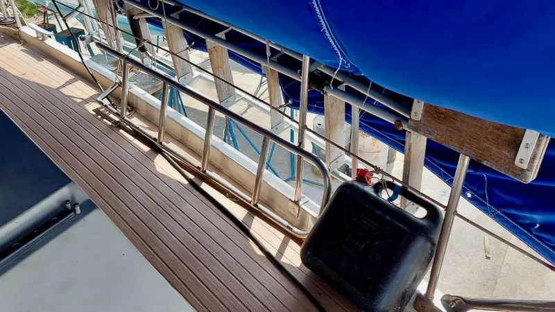 Forever Young Yacht Photos Pics Deck view of 2000 Amel Super Maramu sailboat with blue canopy and wooden flooring.