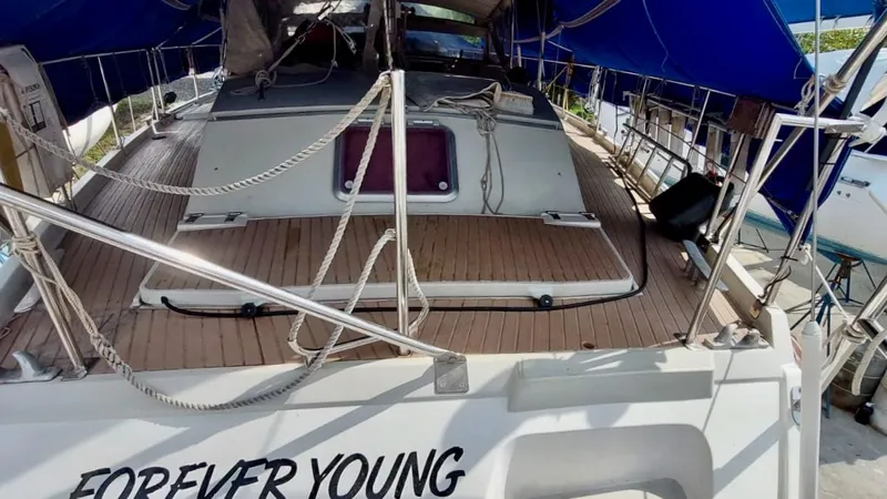 Forever Young Yacht Photos Pics Amel Super Maramu 2000 sailboat deck with blue canopy and "Forever Young" text.