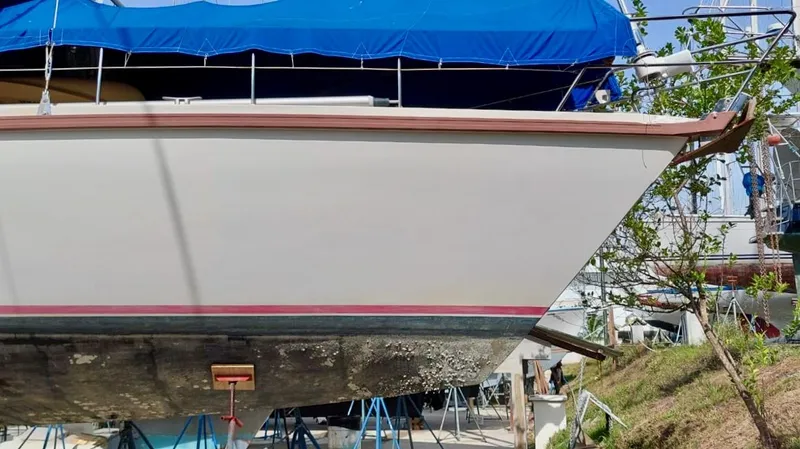 Forever Young Yacht Photos Pics Amel Super Maramu 2000 sailboat on dry dock, blue tarp cover, side view.
