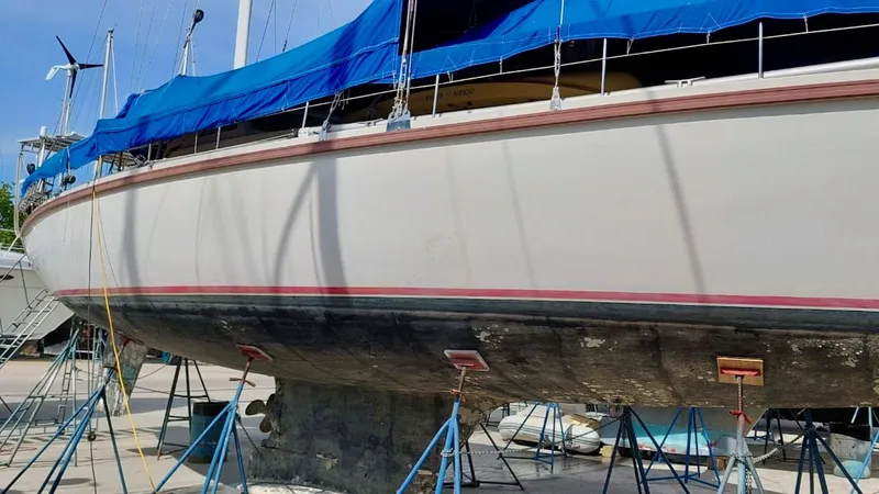 Forever Young Yacht Photos Pics Amel Super Maramu 2000 sailboat on stands, blue tarp cover, side view.