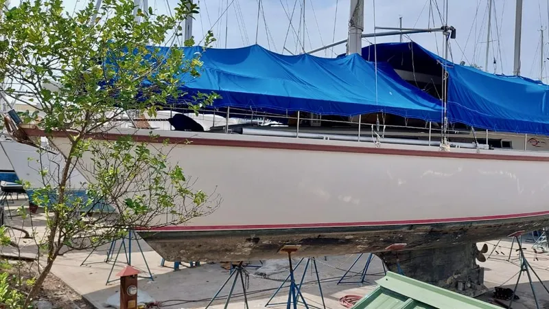 Forever Young Yacht Photos Pics Amel Super Maramu 2000 sailboat on stands, covered with a blue tarp.
