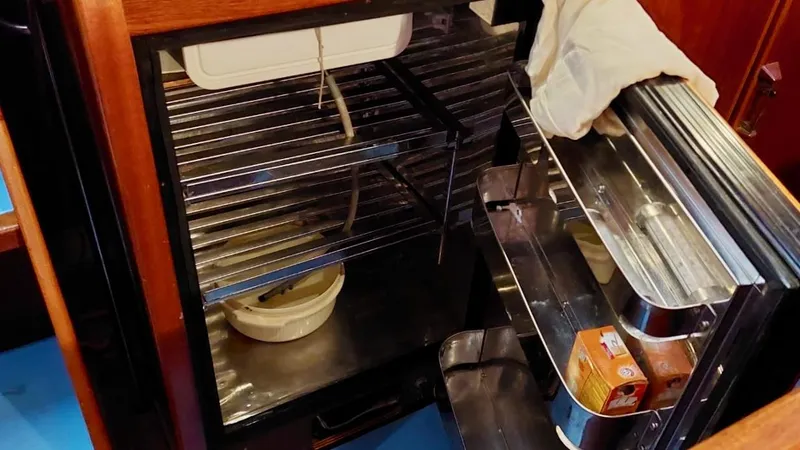 Forever Young Yacht Photos Pics Open refrigerator inside Amel Super Maramu 2000 yacht, showing shelves and stored items.