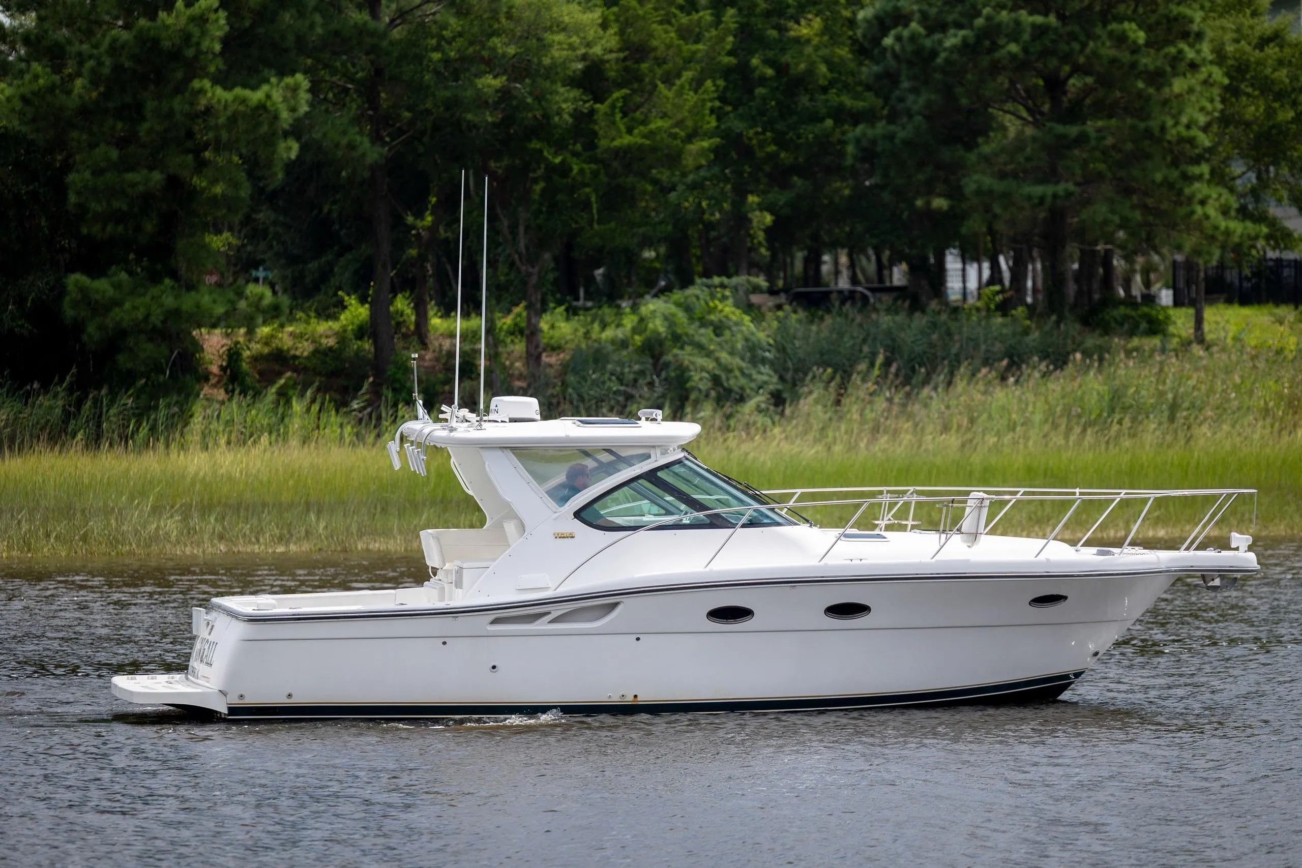 2004 Tiara Yachts 3200 Open cruising on a serene waterway with lush greenery.