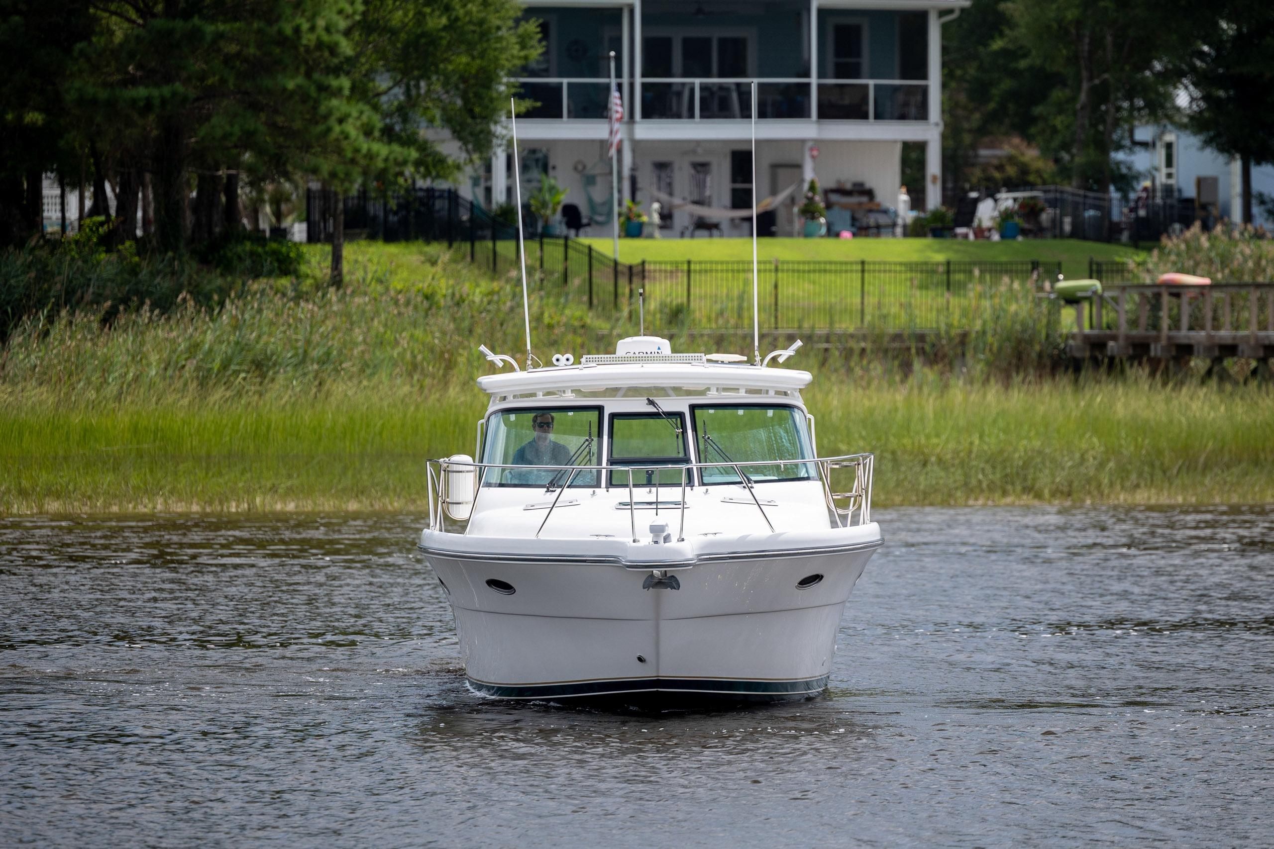 2004 Tiara Yachts 3200 Open cruising on a serene river near a lush green shoreline.