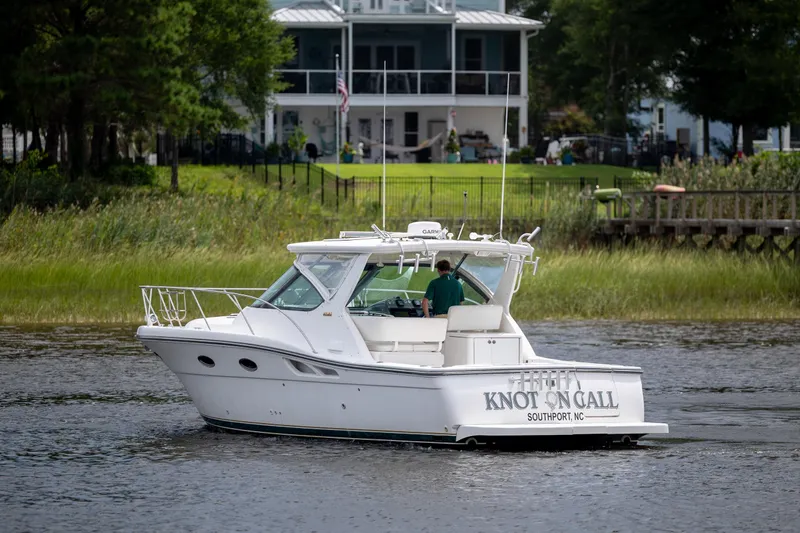 Knot On Call Yacht Photos Pics 2004 Tiara Yachts 3200 Open boat cruising near a waterfront home.