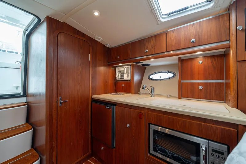 Knot On Call Yacht Photos Pics 2004 Tiara Yachts 3200 Open interior with wooden cabinetry and modern kitchen amenities.