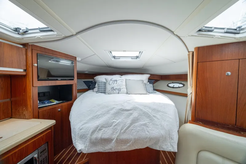 Knot On Call Yacht Photos Pics 2004 Tiara Yachts 3200 Open cabin interior with bed, TV, and wooden cabinetry.