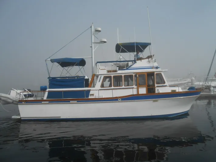  Yacht Photos Pics 1983 Californian 42 yacht on calm water, featuring blue and white design.