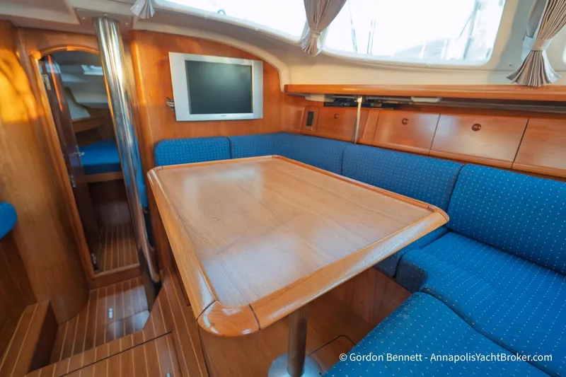 Margaritaville Yacht Photos Pics Interior of 2004 Jeanneau Sun Odyssey 43 DS yacht with wooden table and blue seating.