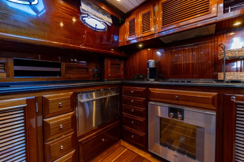 Holly Ann Yacht Photos Pics Luxurious wooden kitchen interior of 2010 Vicem 64 Classic yacht, featuring modern appliances.