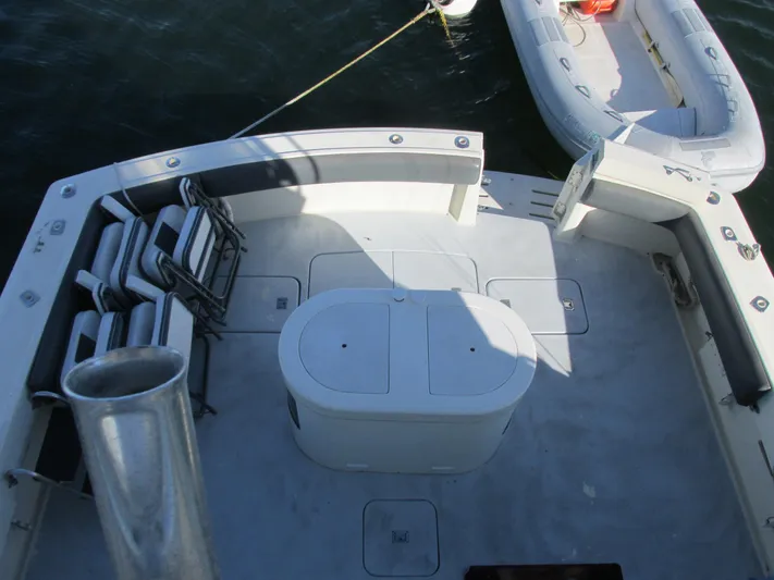 My Way IV Yacht Photos Pics 1987 Hatteras Convertible boat deck with seating and storage, docked beside an inflatable dinghy.