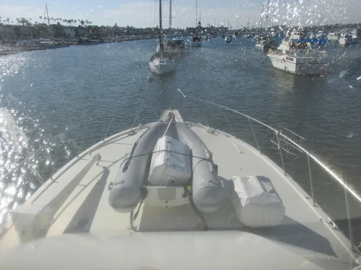 My Way IV Yacht Photos Pics 1987 Hatteras Convertible yacht navigating a marina, with inflatable dinghy on deck.