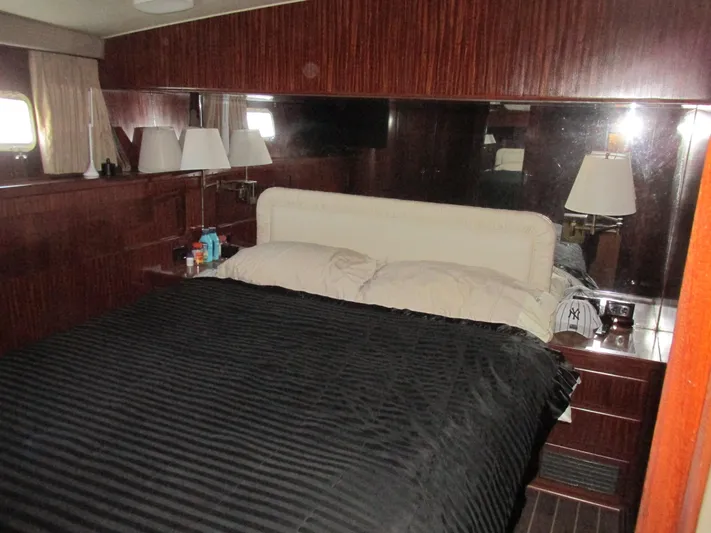 My Way IV Yacht Photos Pics Luxurious bedroom interior of a 1987 Hatteras Convertible yacht with wood paneling and cozy bedding.