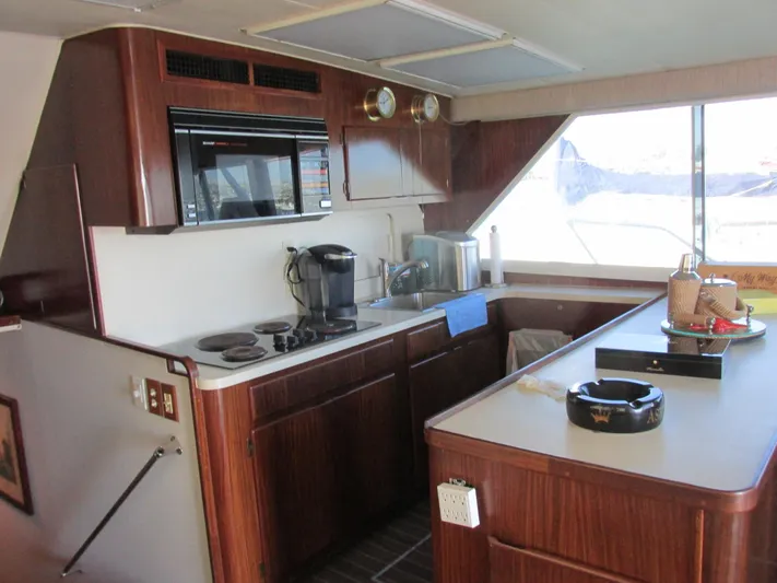 My Way IV Yacht Photos Pics Interior of a 1987 Hatteras Convertible yacht kitchen with wood cabinetry and modern appliances.