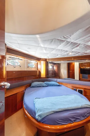 Princess V65 Yacht Photos Pics Luxurious cabin interior of 2003 Princess V65 yacht with cozy bedding and elegant wood finishes.