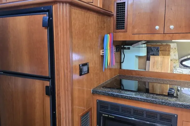  Yacht Photos Pics 2005 Cruisers Yachts 440 Express kitchen with wooden cabinetry and modern appliances.