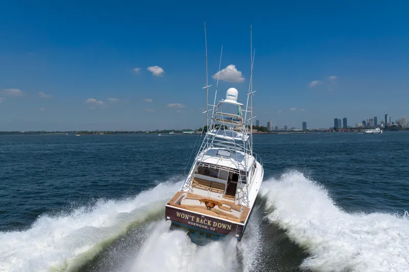  Yacht Photos Pics 2012 Cabo 44 Hardtop Express yacht cruising on open water, city skyline in background.
