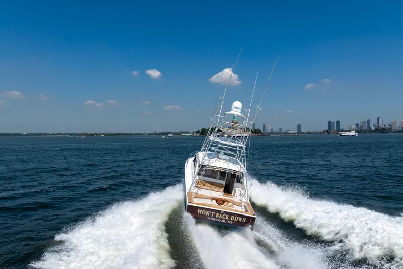  Yacht Photos Pics 2012 Cabo 44 Hardtop Express cruising on open water with city skyline in background.