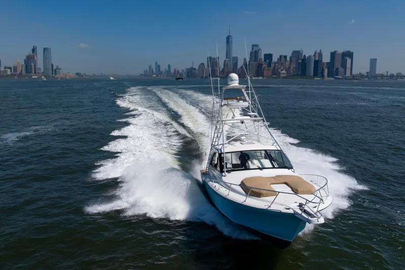  Yacht Photos Pics 2012 Cabo 44 Hardtop Express cruising near city skyline on a sunny day.