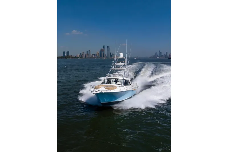  Yacht Photos Pics 2012 Cabo 44 Hardtop Express cruising on water with city skyline in background.